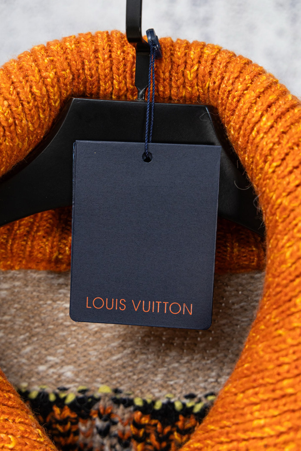 Beige knit sweater interior neckline with Louis Vuitton tag on hanger