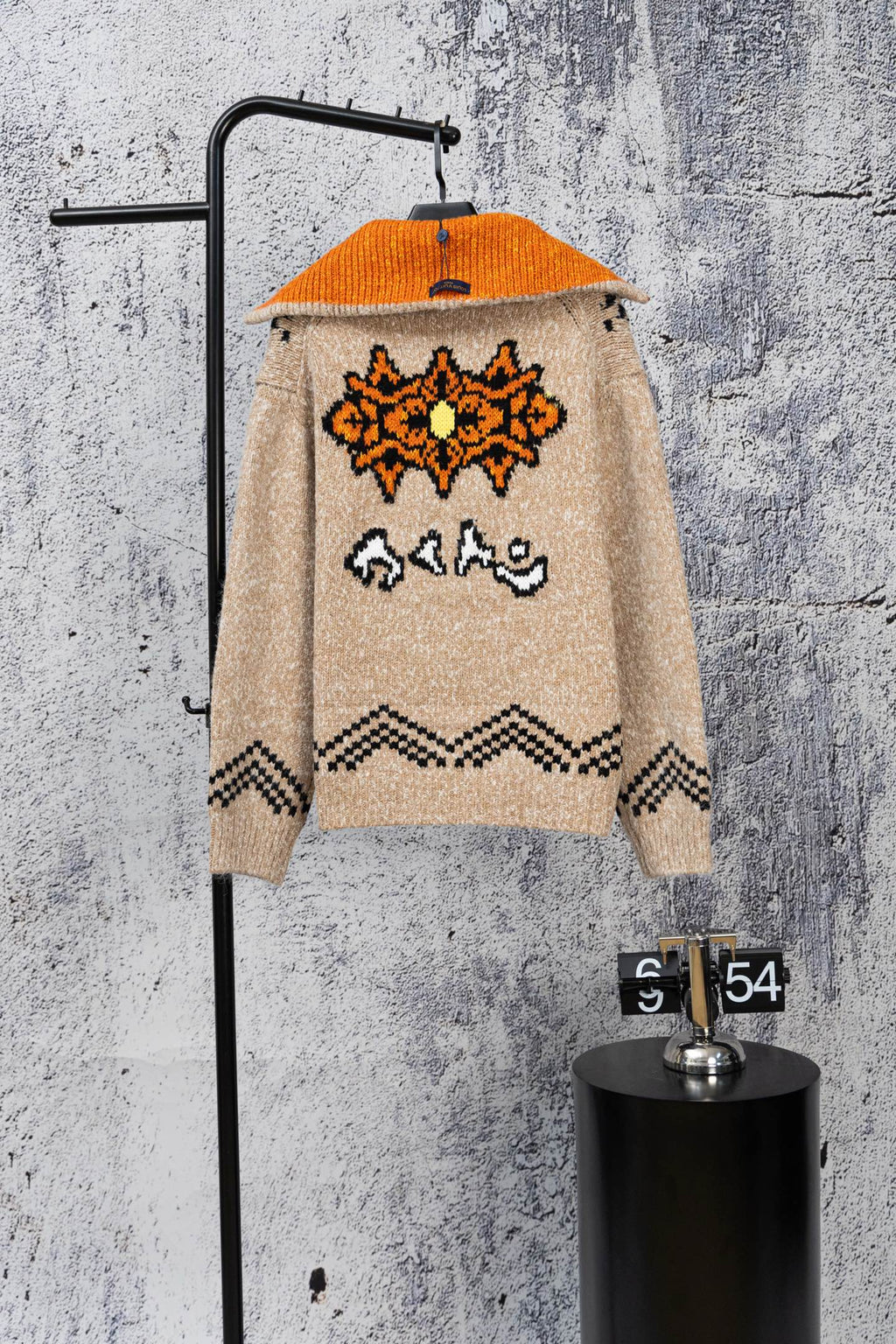 Beige knit zip-up sweater with orange hood and back orange-and-black graphic design