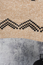 Beige knit sweater with black zigzag band across hemline
