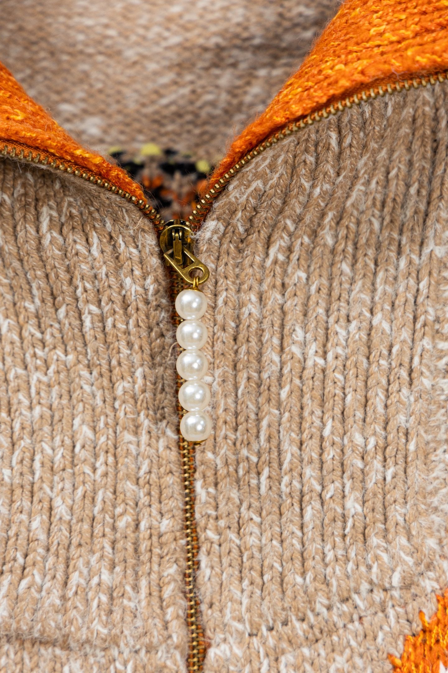 Beige knit cardigan zipper pull with faux pearl and gold-toned chain