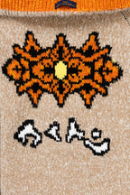 Beige knit zip-up sweater front with orange-and-black snowflake graphic and striped motifs