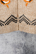 Beige knit zip-up sweater close-up with black zigzag and orange motifs across chest