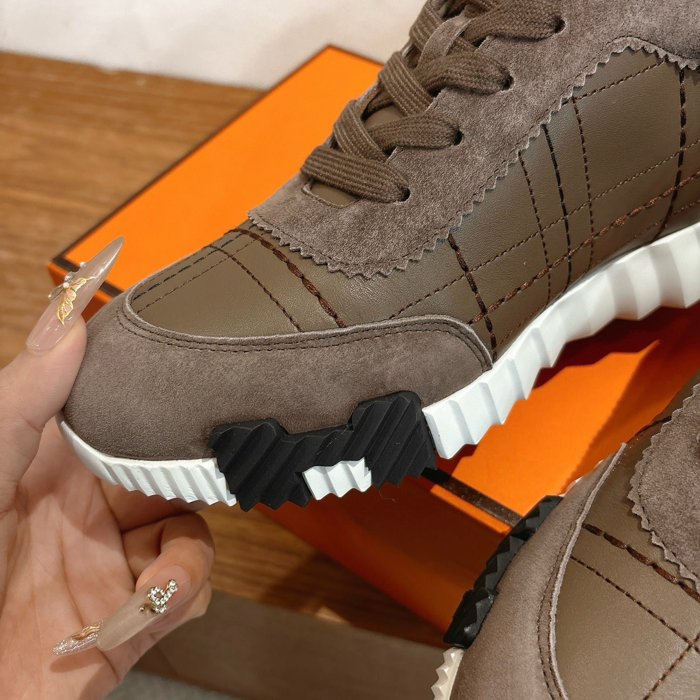 Gray sneaker side view with lace eyelets, quilted paneling, and white sole