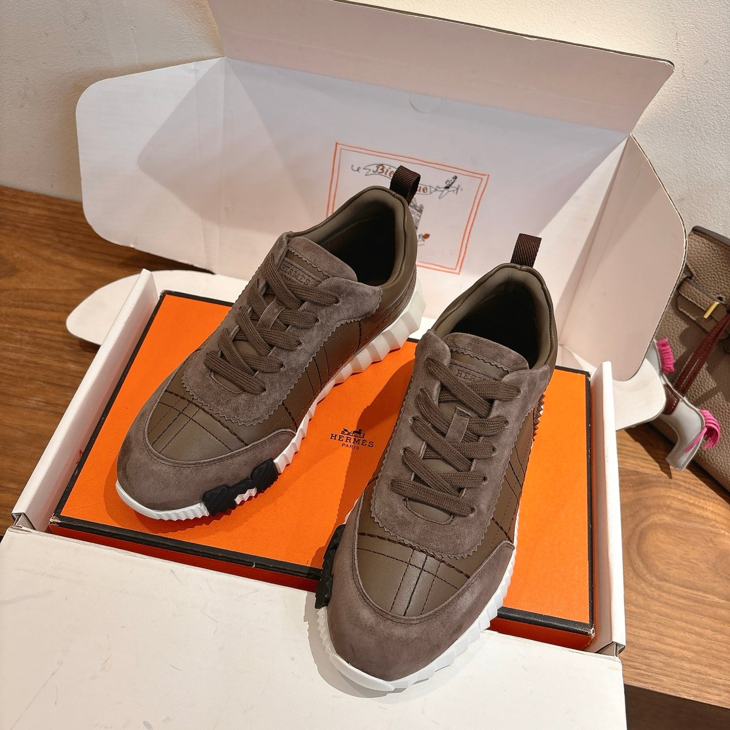 Gray lace-up sneakers inside an open box, with padded collar and rubber sole