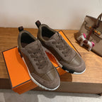 Gray lace-up sneakers on orange box, with side stitching and rubber sole