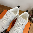 Hermes unisex white sneakers close-up, lace-up with black grid stitching, textured sole.