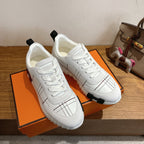 Hermes unisex white sneakers on box, lace-up design with black grid stitching, rubber sole.