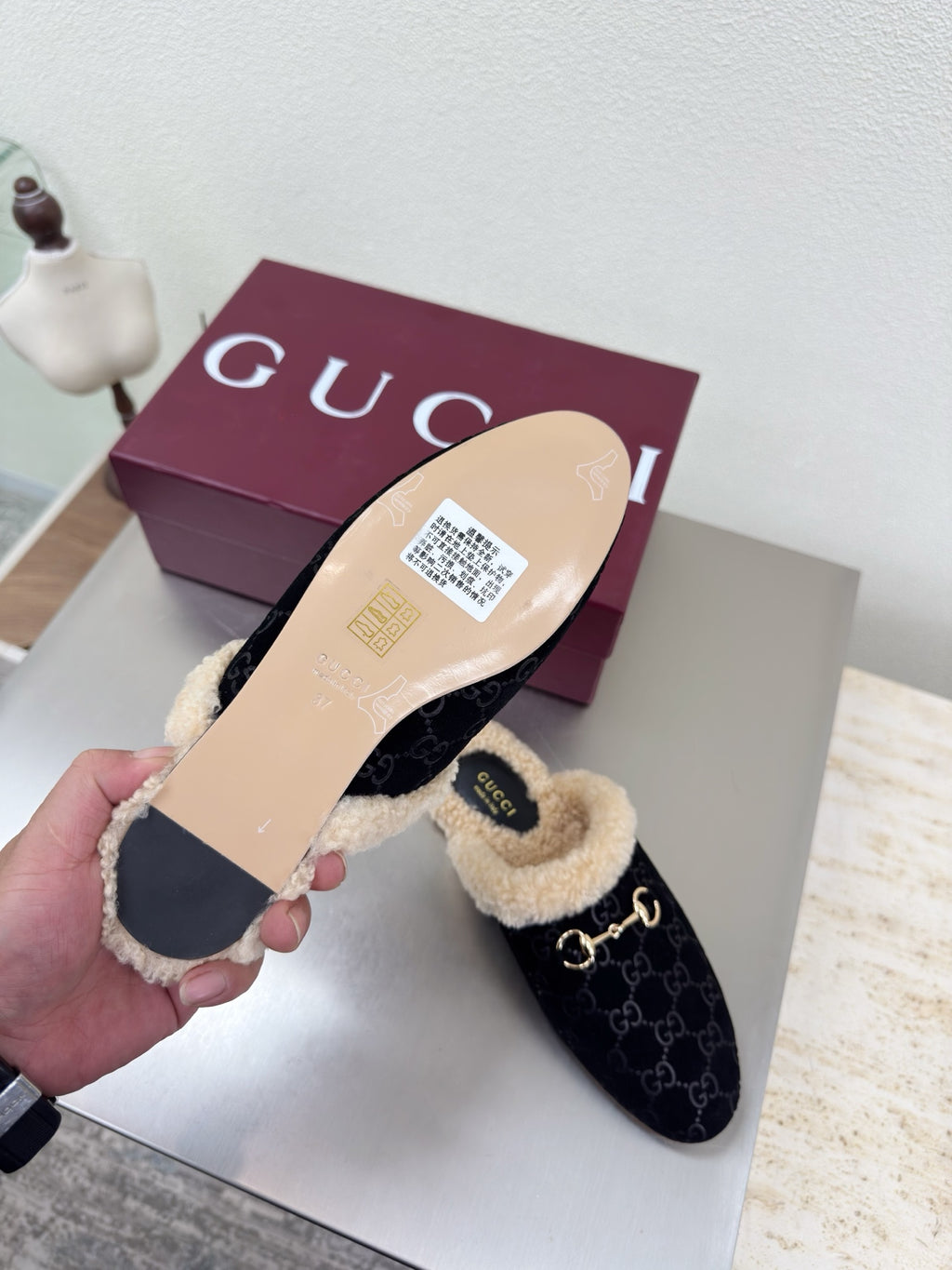 Gucci mule with black GG upper and beige shearling lining; flat tan sole shown.