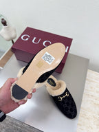 Gucci mule with black GG upper and beige shearling lining; flat tan sole shown.