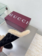 Black Gucci mules with beige shearling trim and GG pattern, viewed from top-left.
