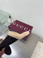 Gucci women’s slipper held sideways, dark monogram with tan shearling strap and gold bit