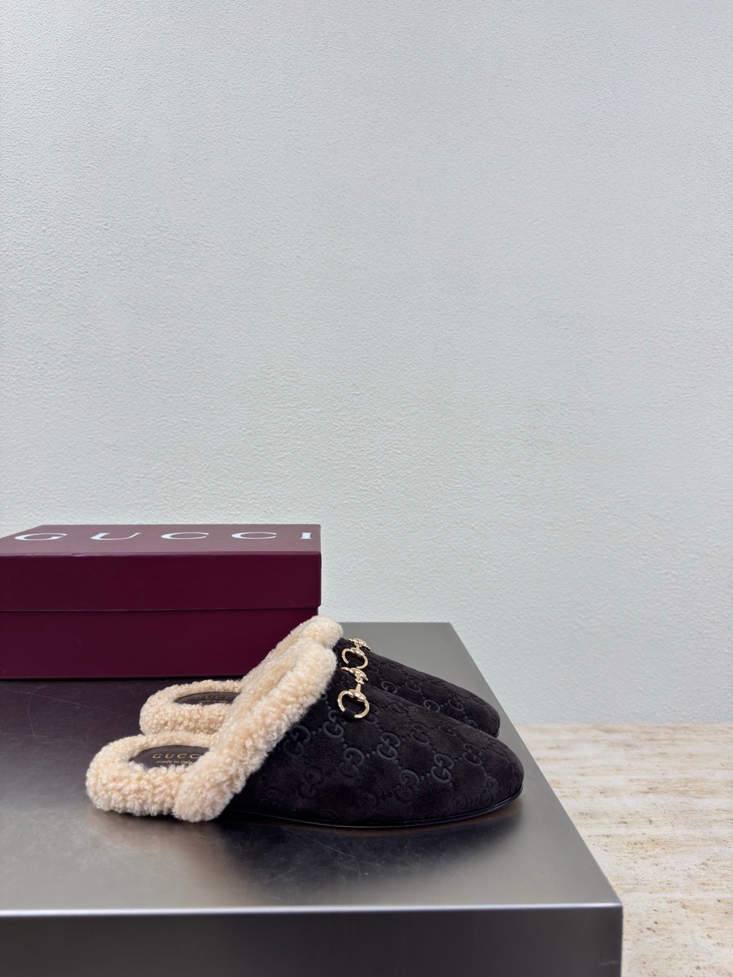 Gucci women’s dark slip-on shoe with tan shearling cuff and gold bit detail on top