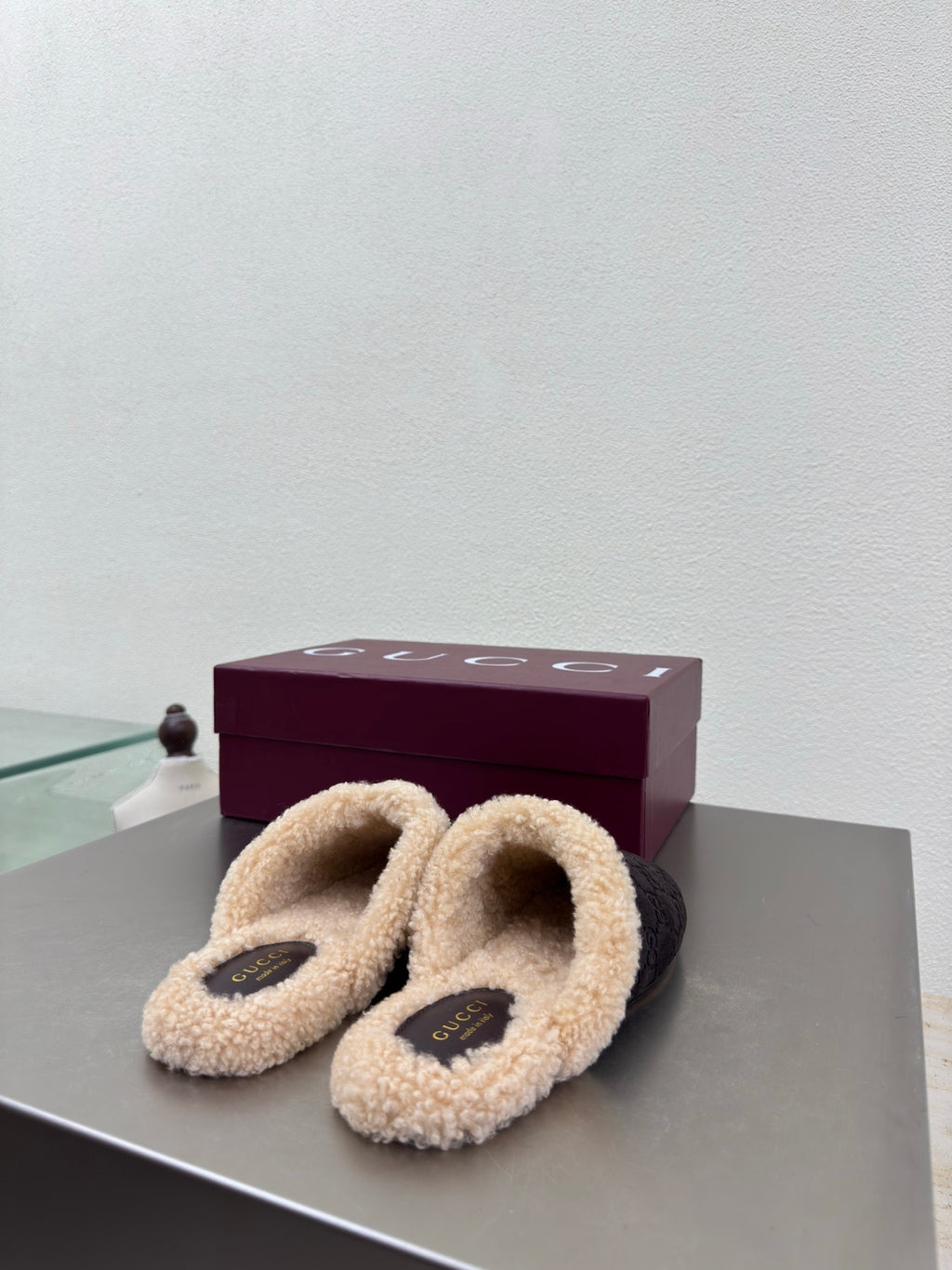 Gucci women’s slippers with dark uppers, tan shearling straps, and gold bit accents