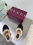 Gucci women’s slippers pair, dark monogram fabric with tan shearling lining and gold bit