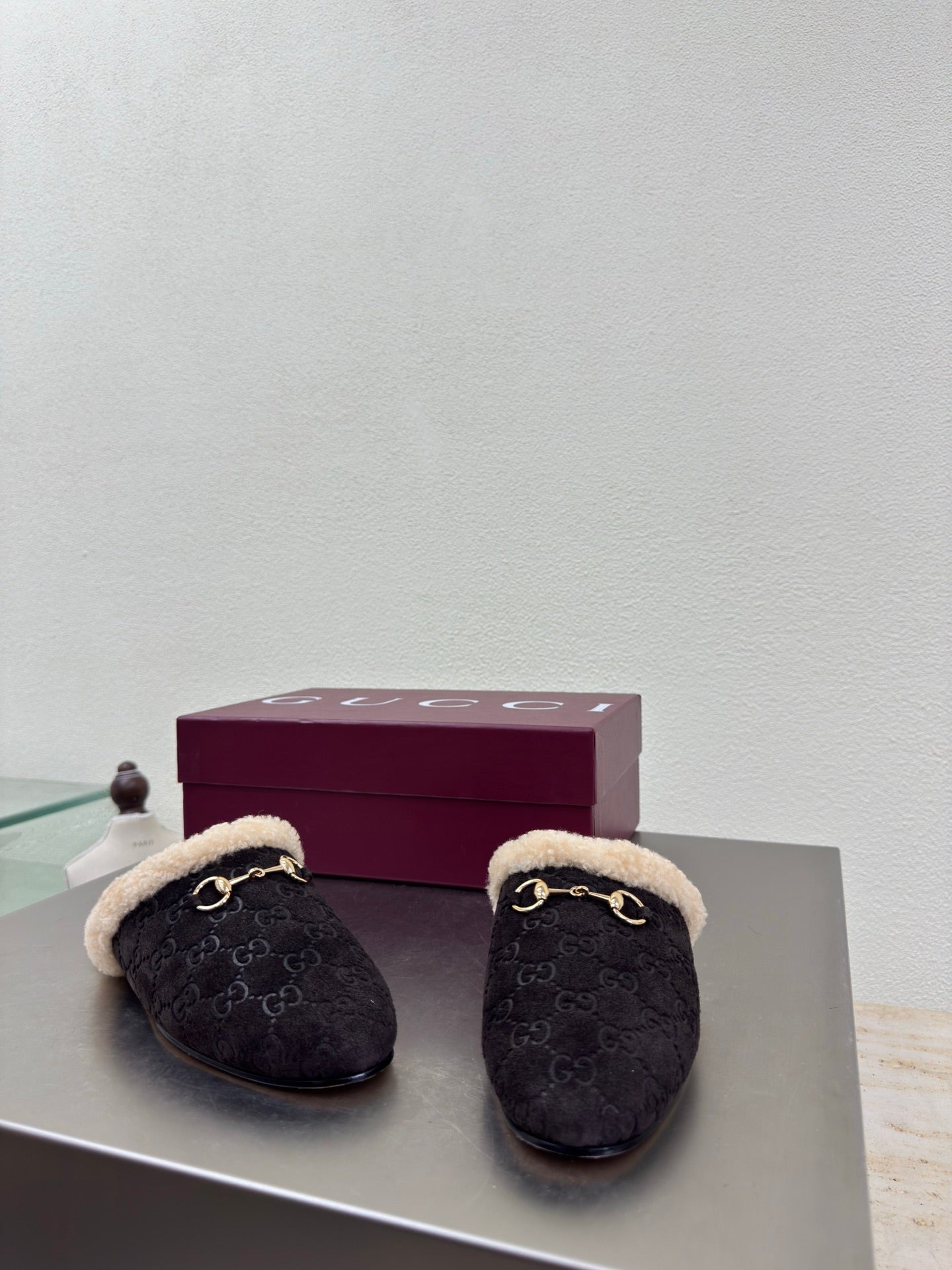 Gucci women’s slippers pair, dark monogram uppers with tan shearling and gold bit detail