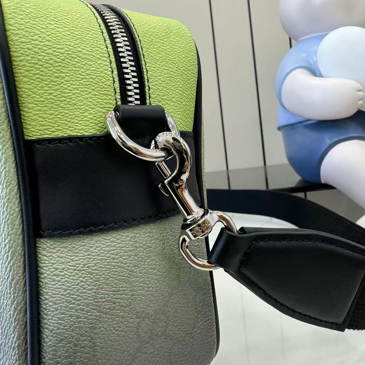 Gucci crossbody bag detail: silver-tone ring clasp, black strap, lime green panels.