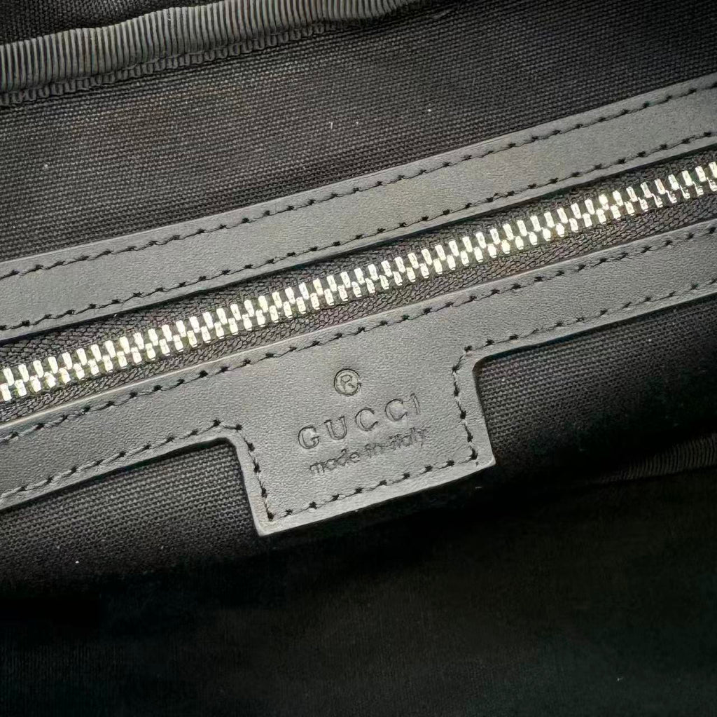 Gucci interior label on dark lining with stitching and zip pocket detail.
