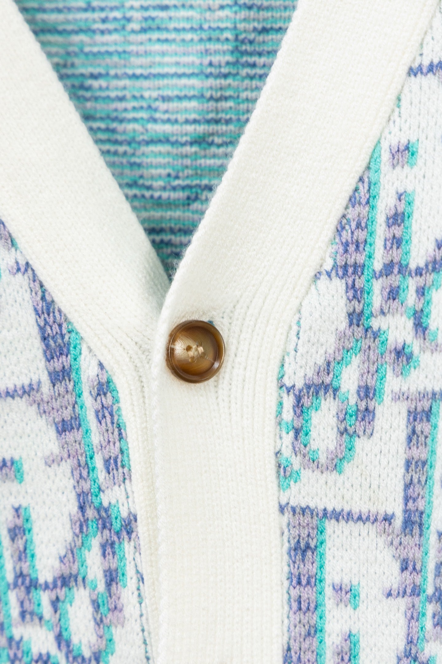 Cardigan front close-up showing gold-tone button and white ribbed edge
