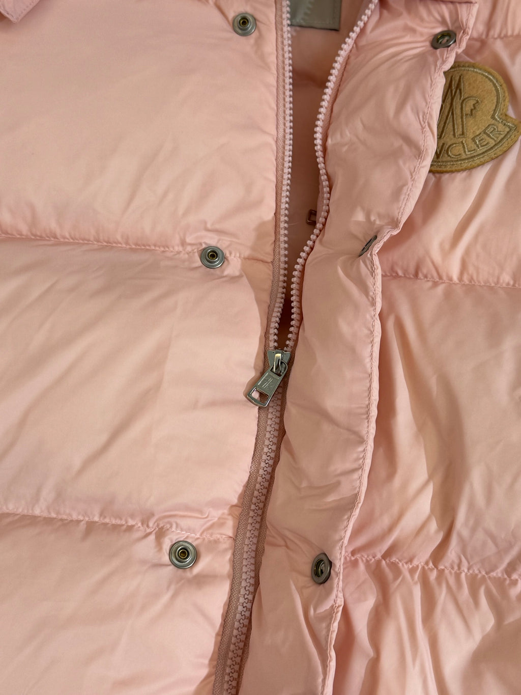 Moncler long puffer jacket, close-up of front zipper and snap buttons on pink fabric