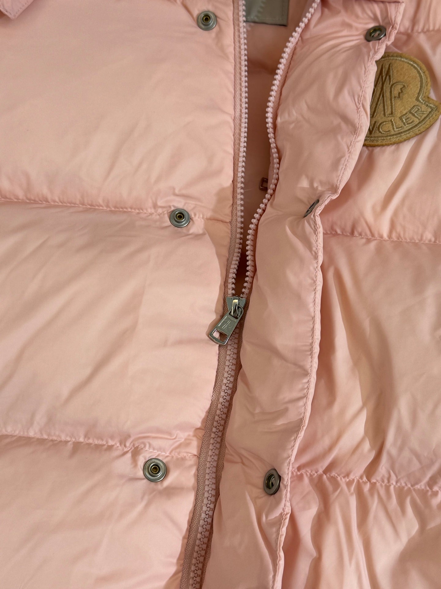 Moncler long puffer jacket, close-up of front zipper and snap buttons on pink fabric