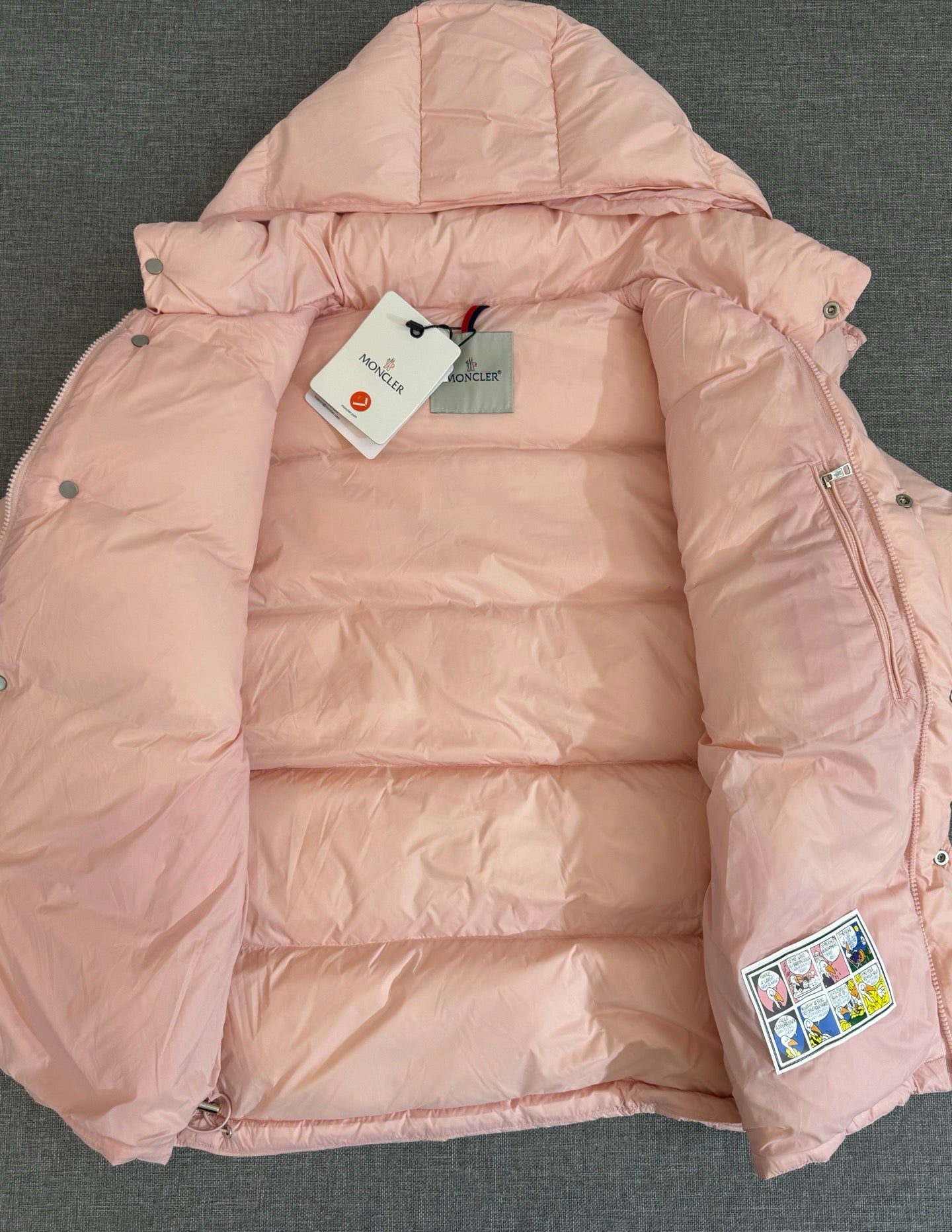 Moncler long puffer jacket laid open, pink interior lining and hood with tags