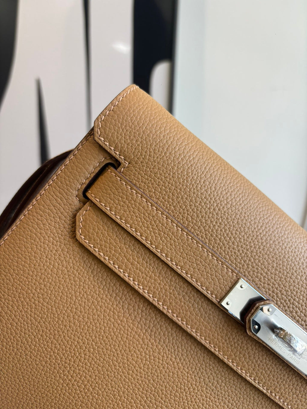 Hermes tan leather bag close-up of front strap and metal lock