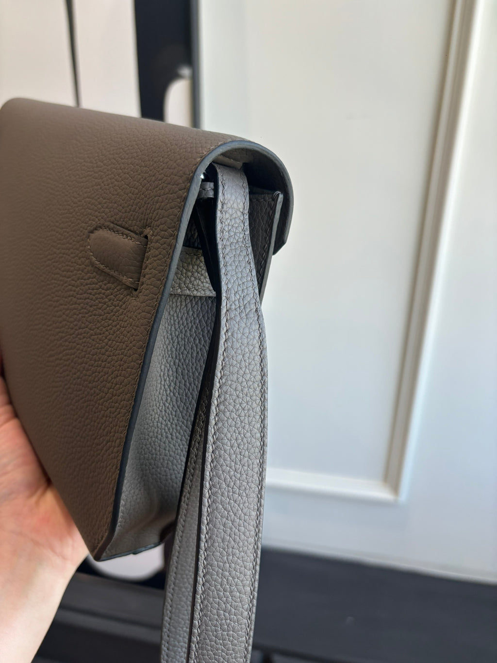 Hermes leather bag side view, textured gray with long strap and dark interior