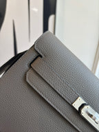 Hermes leather flap bag close-up, textured gray with double buckle clasp in silver