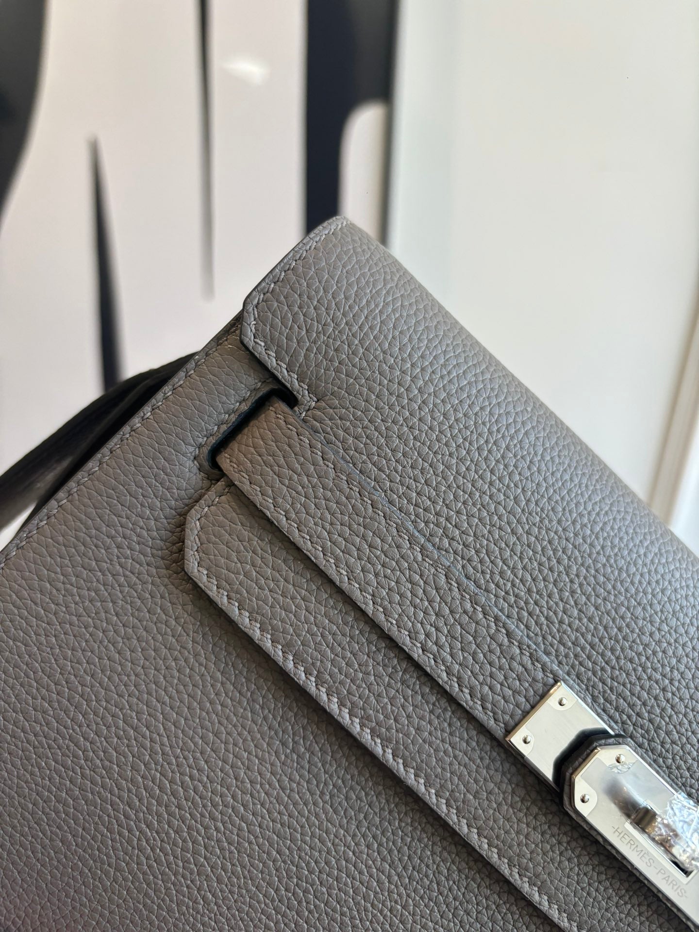 Hermes leather flap bag close-up, textured gray with double buckle clasp in silver