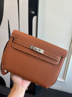 Hermes flap bag in brown leather with front strap closure and top handle
