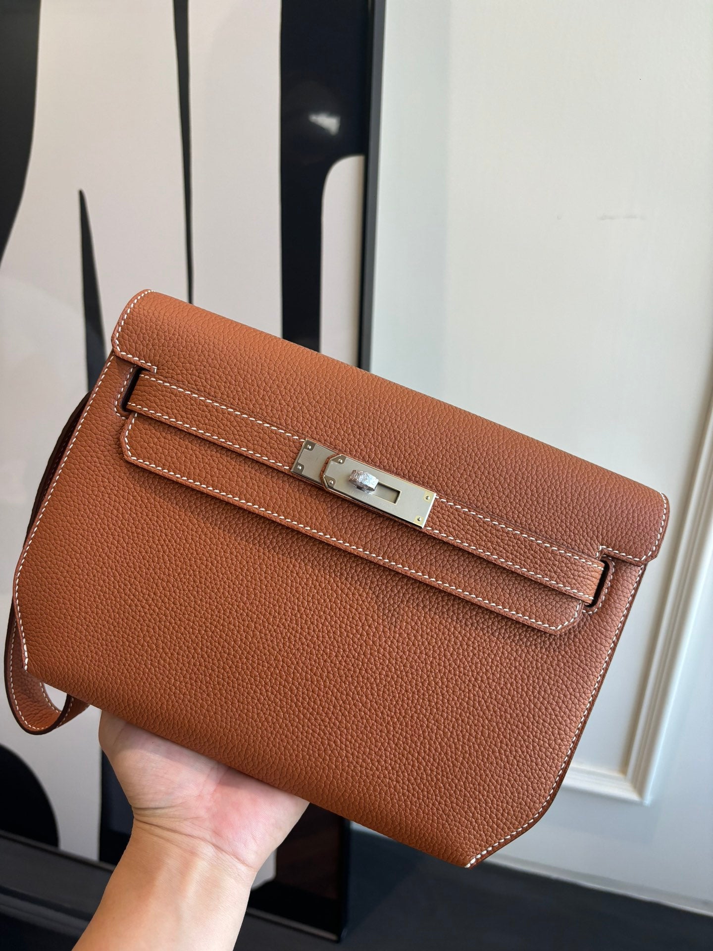 Hermes flap bag in brown leather with front strap closure and top handle