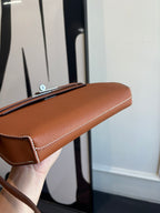 Hermes brown leather flap bag angled view with front edge and stitched trim