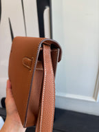 Hermes brown leather flap bag side view with interior lining and stitched strap