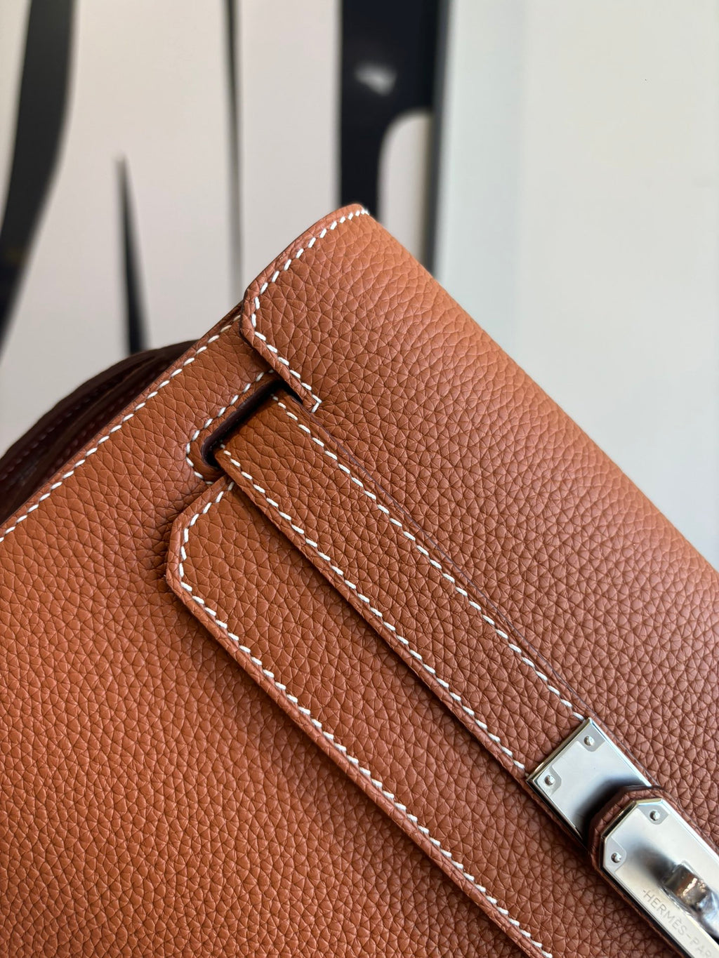 Hermes brown leather flap bag detail with stitched strap and silver clasp hardware