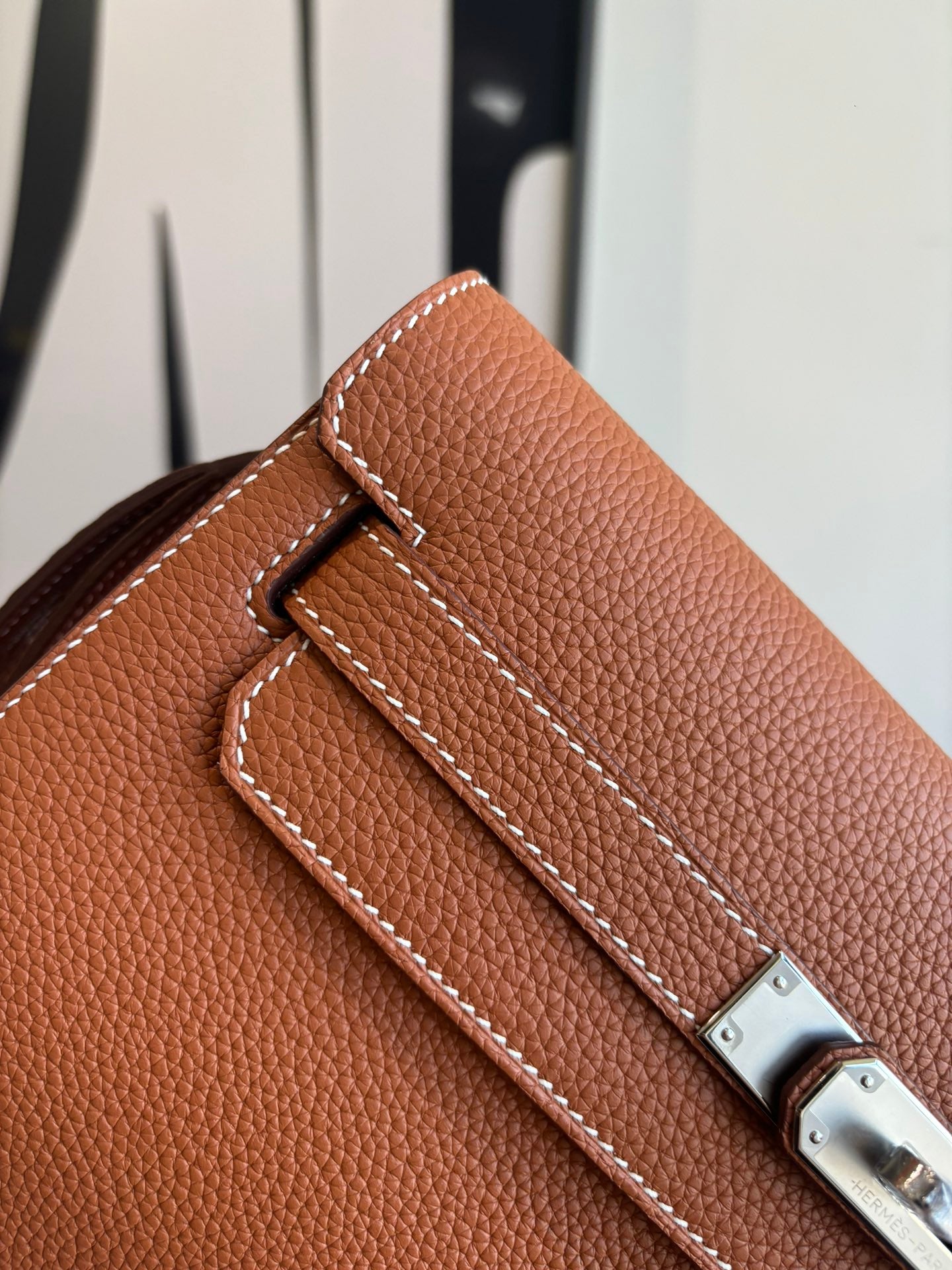 Hermes brown leather flap bag detail with stitched strap and silver clasp hardware