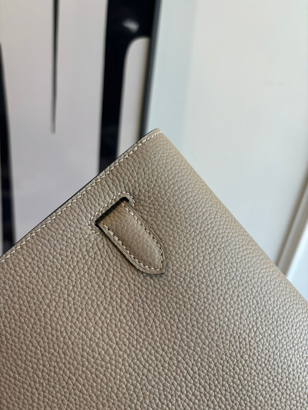 Hermes bag exterior close-up with stitched front tab on textured taupe leather