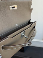 Hermes leather bag interior close-up, taupe lining with front pocket and silver clasp