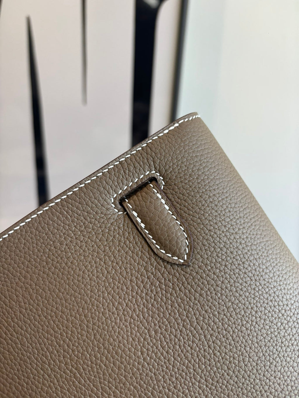 Hermes leather bag buckle detail, taupe pebbled texture and stitched strap tab
