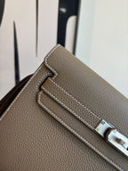 Hermes leather bag front flap close-up, taupe texture with silver lock plate