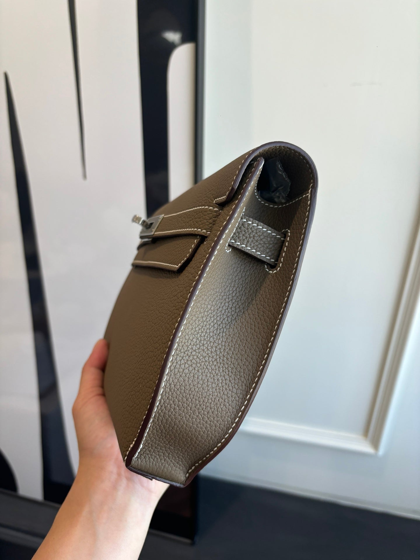 Hermes leather bag side view, taupe body with adjustable shoulder strap and stitching