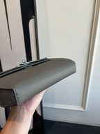 Gray leather flap bag profile with top handle and strap attachment