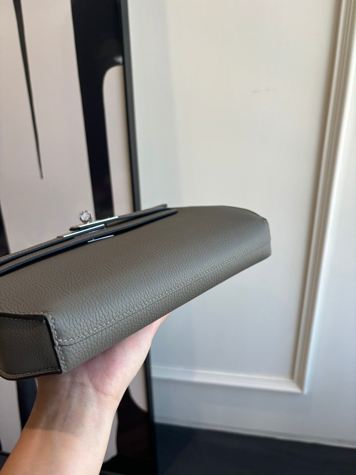 Gray leather flap bag profile with top handle and strap attachment