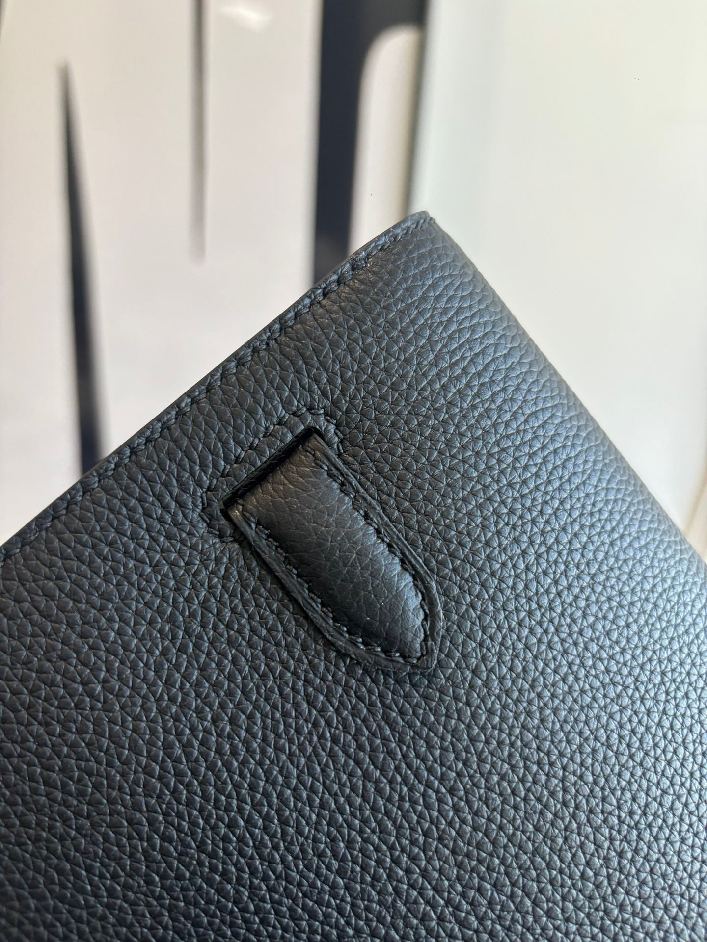 Hermes leather bag front panel close-up with recessed flap tab, textured dark grain