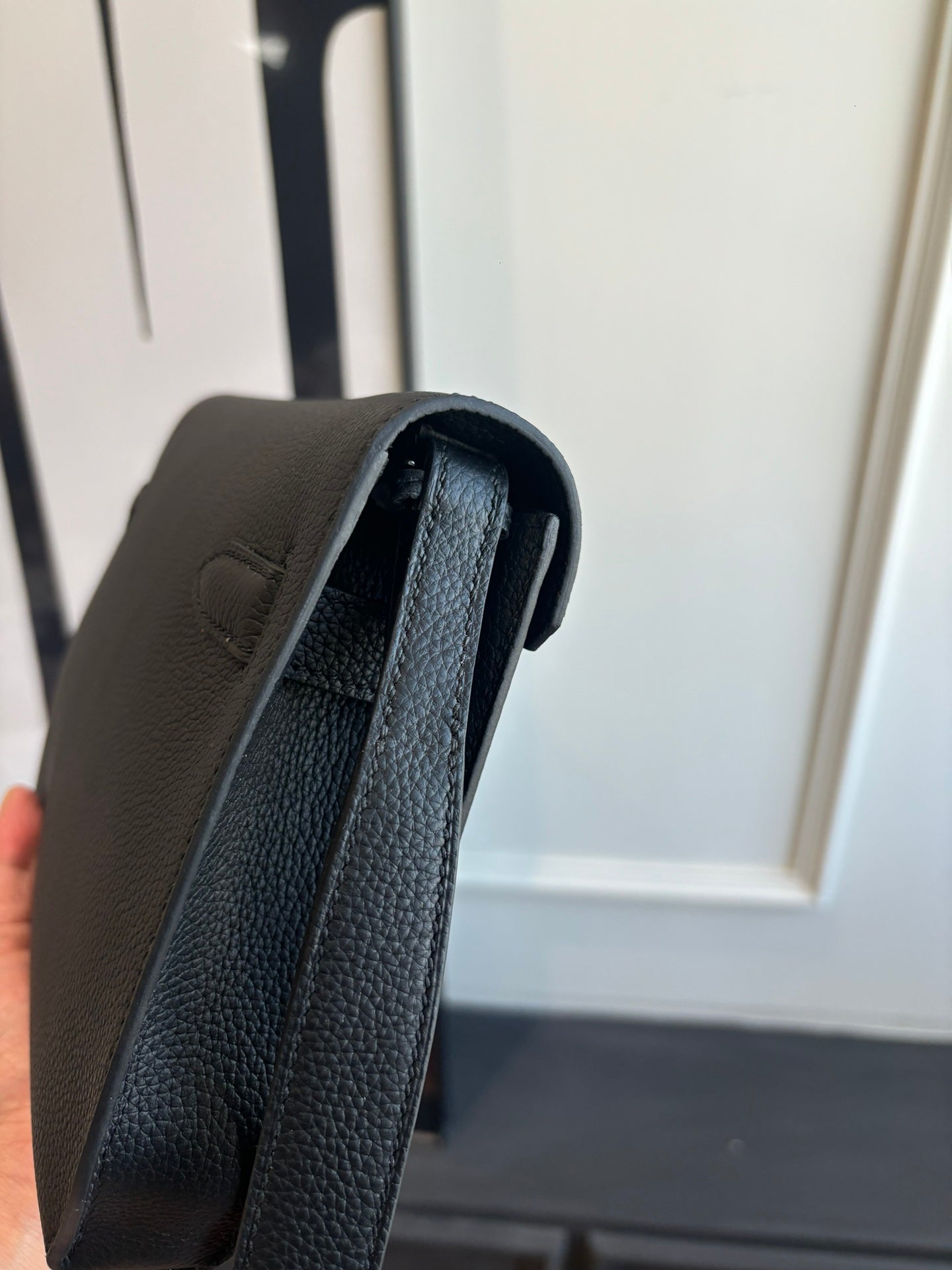 Hermes leather bag edge view showing interior lining, textured dark grain, shoulder strap