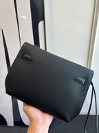 Hermes leather flap bag side view with small flap pockets, textured dark grain, strap