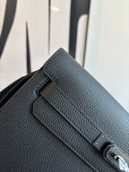 Hermes leather flap bag close-up of front strap tab and metal lock, textured dark grain