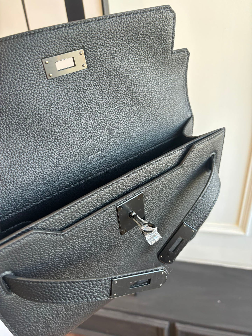 Hermes leather flap bag clasp and interior pocket detail, textured dark grain, metal hardware