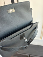 Hermes leather flap bag clasp and interior pocket detail, textured dark grain, metal hardware
