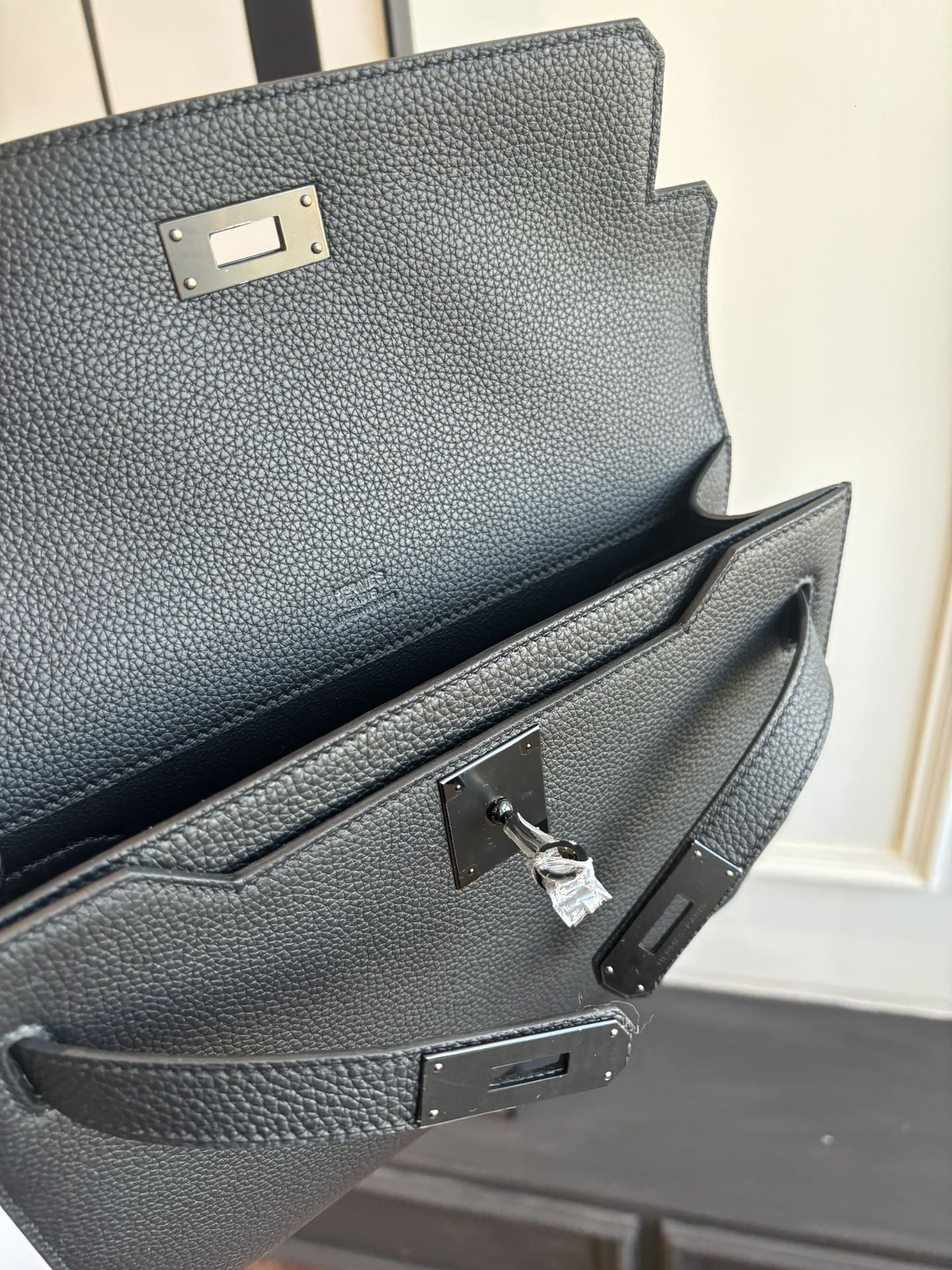 Hermes leather flap bag clasp and interior pocket detail, textured dark grain, metal hardware