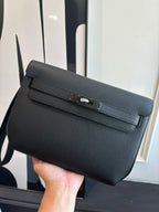 Hermes leather flap bag with front buckle clasp, textured dark grain finish, wrist strap